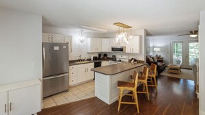 A modern kitchen with white cabinets, stainless steel appliances, and a central island with bar stools. - Four Bedroom Yacht Condo (Grand Rivers)
