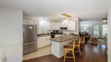A modern kitchen with white cabinets, stainless steel appliances, and a central island with bar stools.