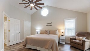 A bedroom with a large bed, a ceiling fan, a window with blinds, and a chair. - Four Bedroom Yacht Condo (Grand Rivers)