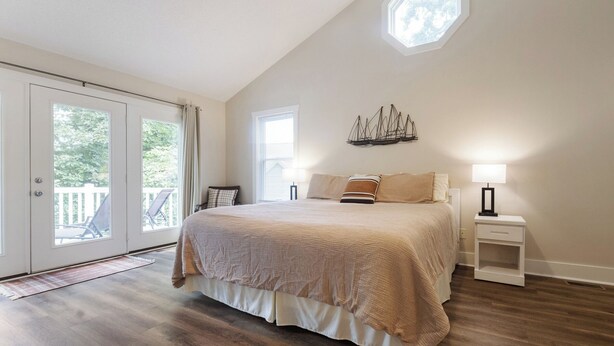 A bedroom with a large bed, a nightstand, a ceiling fan, and a view of the outdoors through a sliding door. - Four Bedroom Yacht Condo (Grand Rivers)