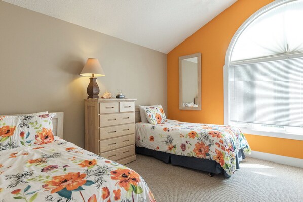 A bedroom with two beds, a dresser, a lamp, and a window with blinds. - Four Bedroom Yacht Condo (Grand Rivers)
