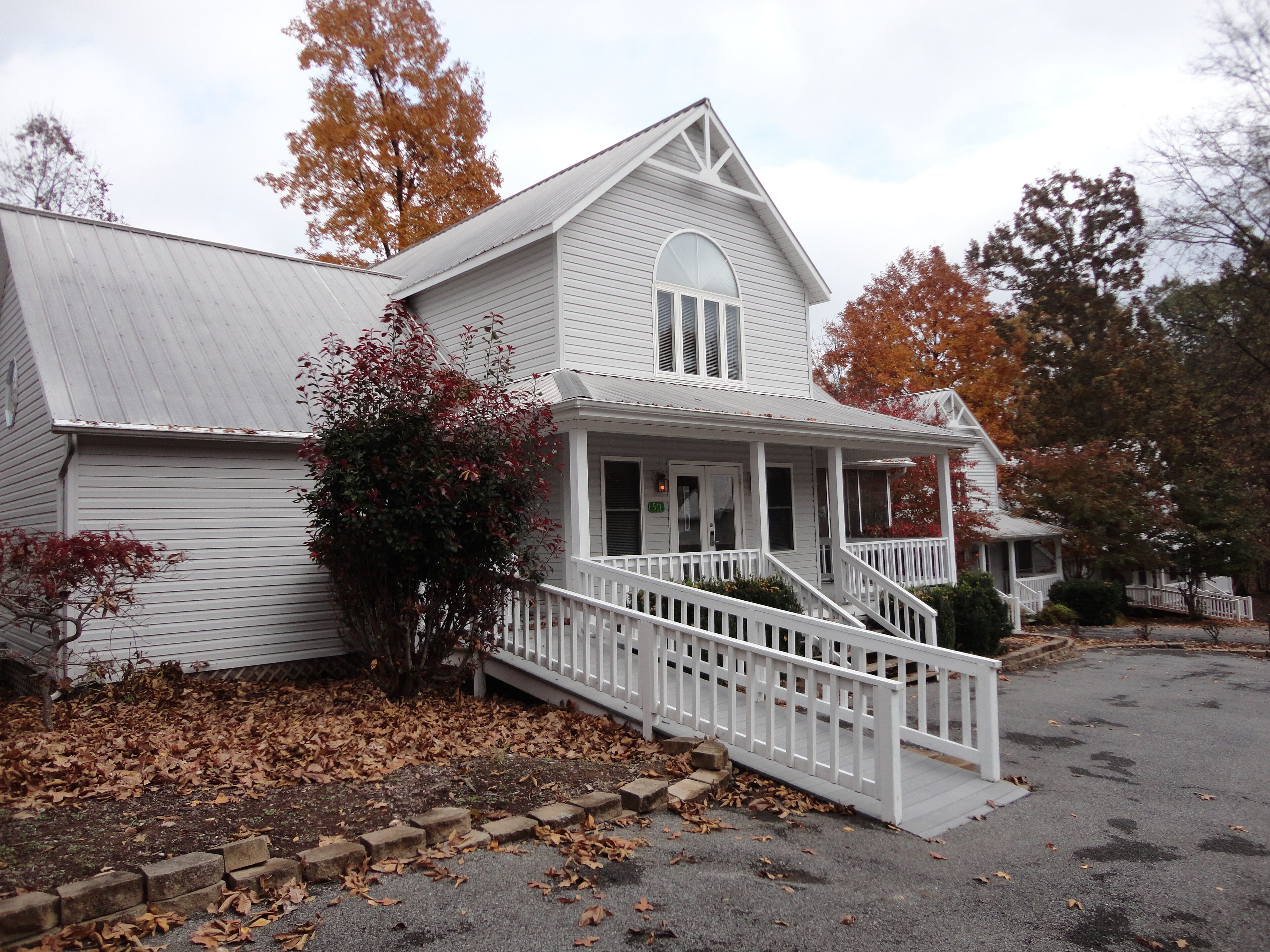 A two-story white building with a porch and a staircase leading to the entrance.