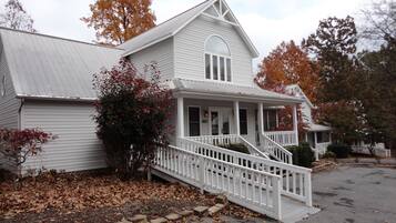 A two-story white building with a porch and a staircase leading to the entrance.