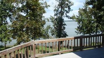 A wooden deck with a view of a lake and trees.