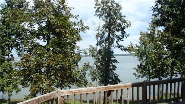 Une terrasse en bois offrant une vue sur un lac et des arbres.