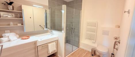 Un baño moderno con ducha acristalada, lavabo blanco y retrete.