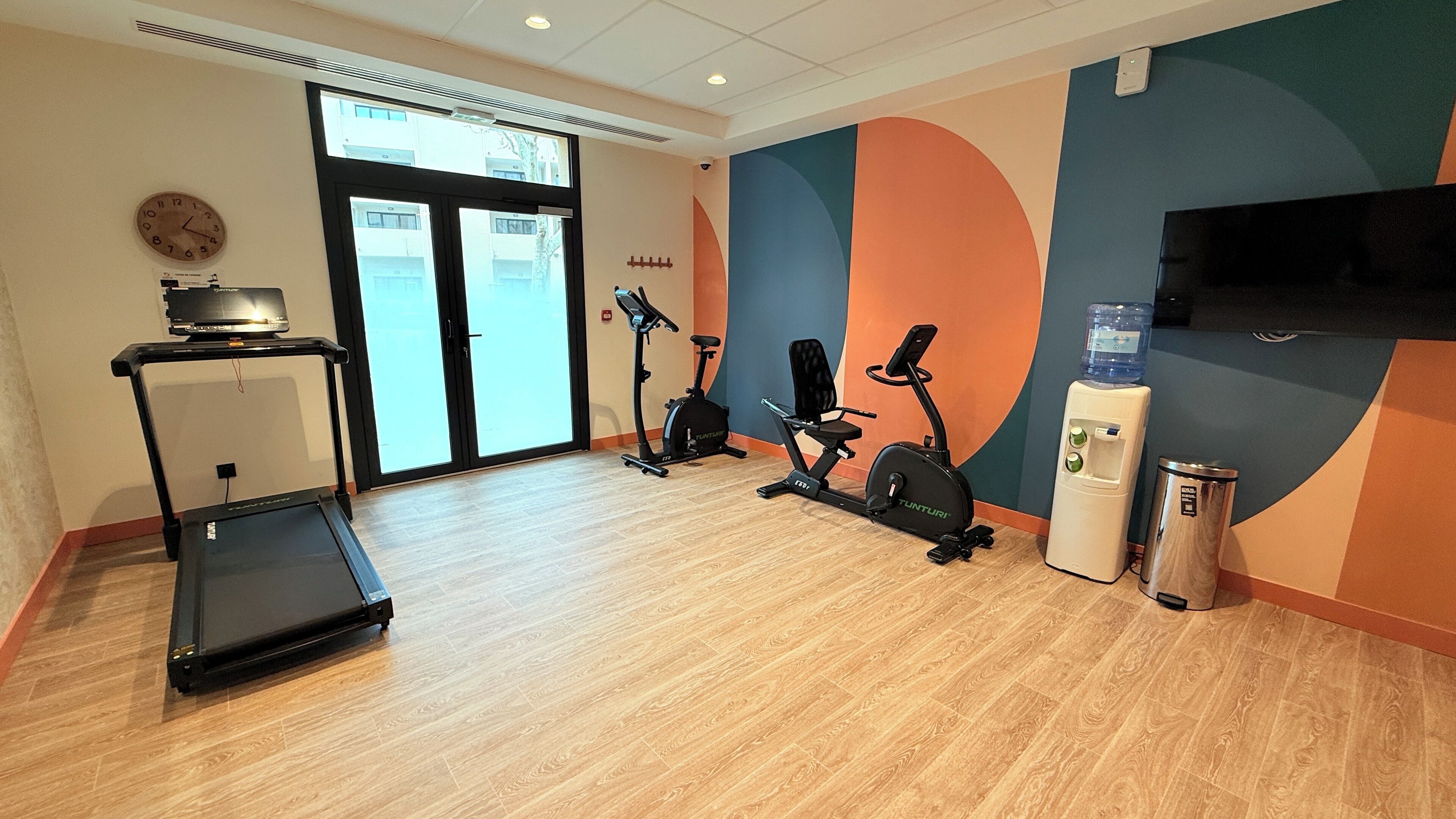 Ein Fitnessstudio mit Laufbändern, Ergometer und Wasserspender.