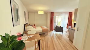 Et hotelværelse med seng, skrivebord, stol, spisebord og et stort vindue.
