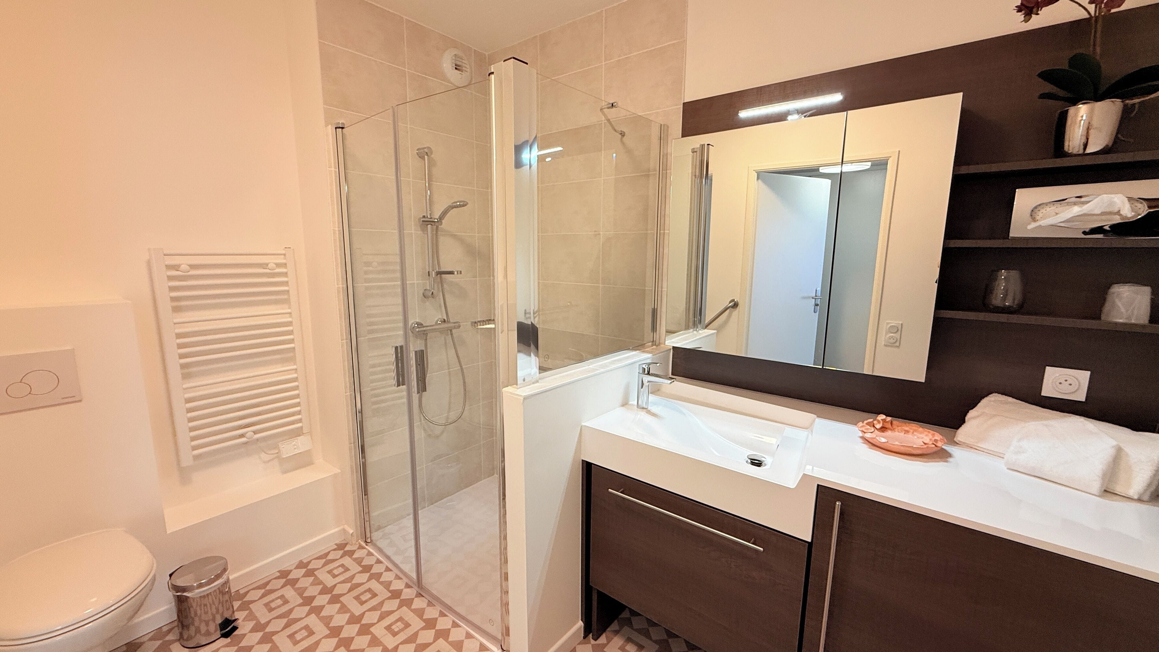 Een moderne badkamer met een glazen douchecabine, een wit wastafelmeubel en een grote spiegel.