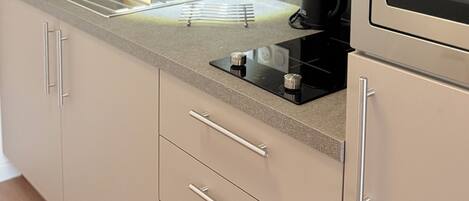 A modern kitchen with a stainless steel sink, a built-in stove, and a microwave.