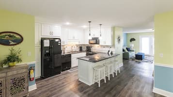 A modern kitchen with white cabinetry, a black refrigerator, and a center island with bar stools.