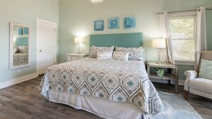 Een slaapkamer met een bed, nachtkastjes, een spiegel en een raam met gordijnen.