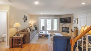 A living room with a sofa, coffee table, TV, fireplace, and a staircase. - Four Bedroom 4.5 Bath Condo (Grand Rivers)