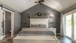 A bedroom with a large bed, a ceiling fan, a window with curtains, and a view of the outdoors. - Four Bedroom Yacht Condo (Grand Rivers)