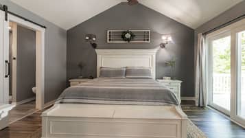 Een slaapkamer met een groot bed, een plafondventilator, een raam met gordijnen en uitzicht op de omgeving.