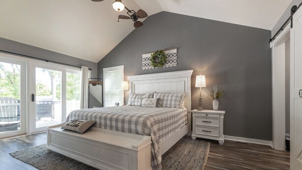 A bedroom with a large bed, a nightstand, a bench, a ceiling fan, and a view of the outdoors. - Four Bedroom Yacht Condo (Grand Rivers)