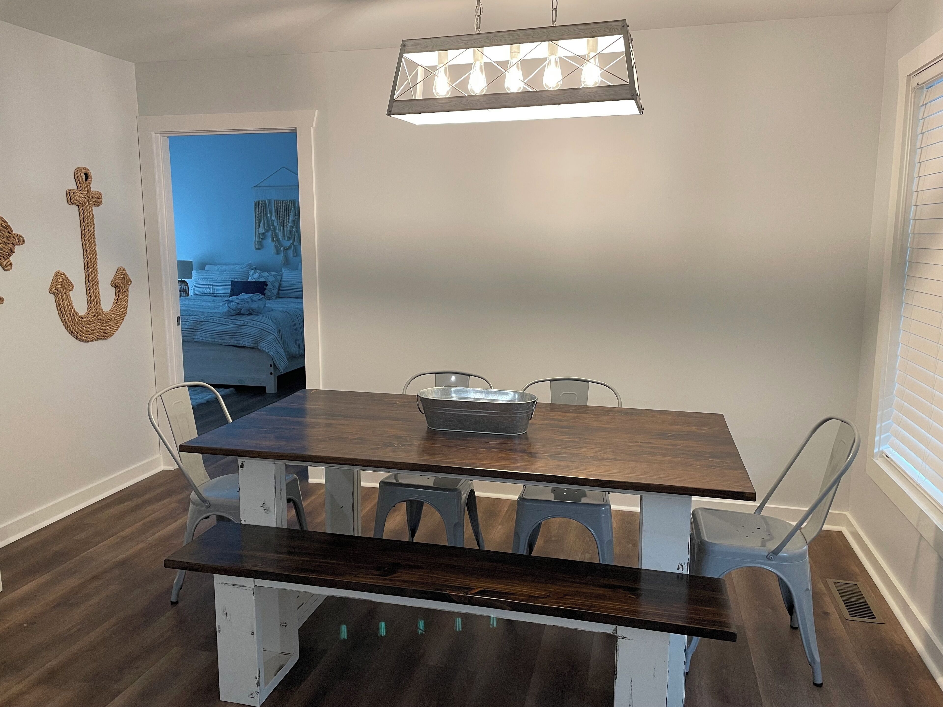 A dining area with a wooden table, metal chairs, and a hanging light fixture.