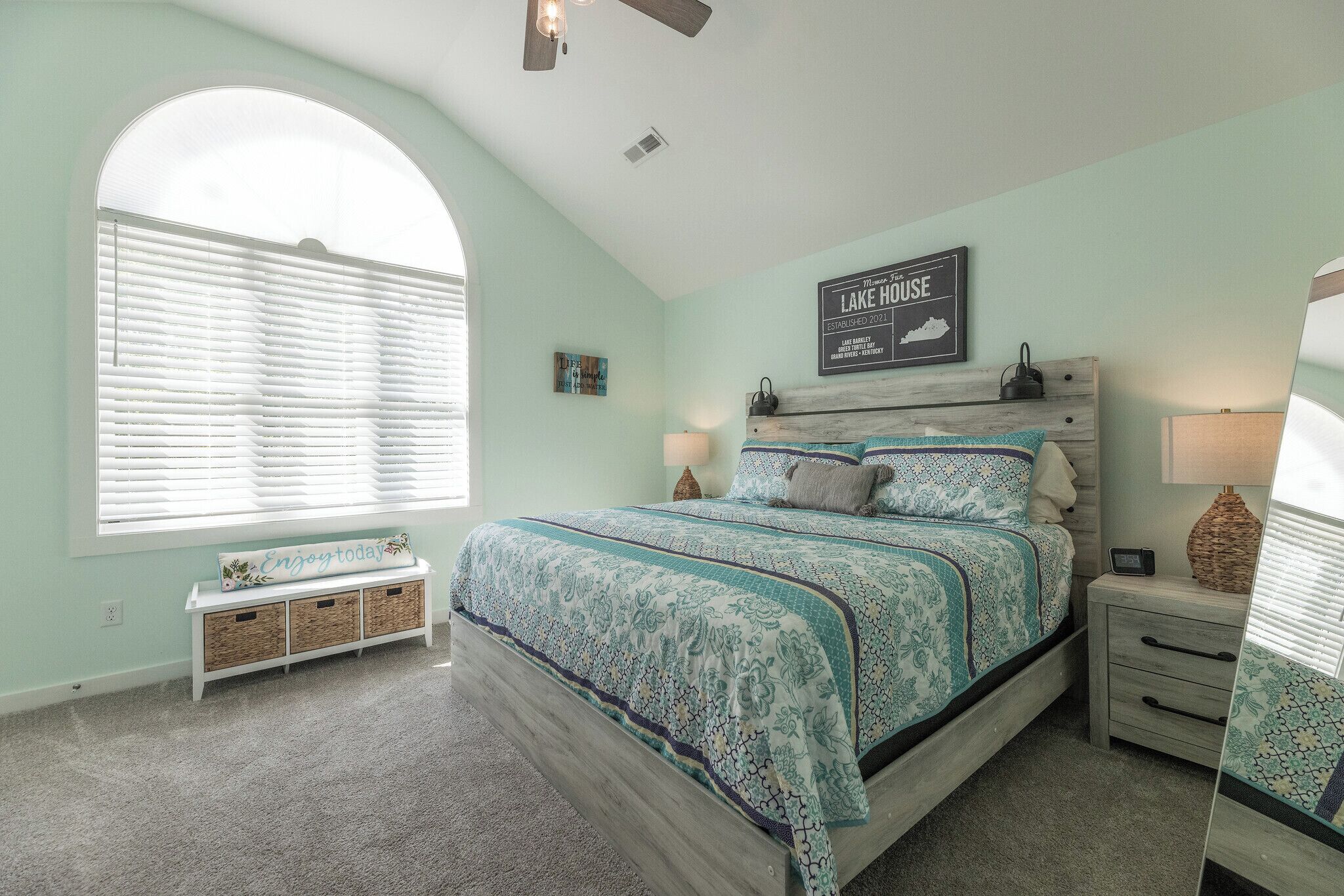 A bedroom with a bed, bedside tables, a bench, and a window with blinds.