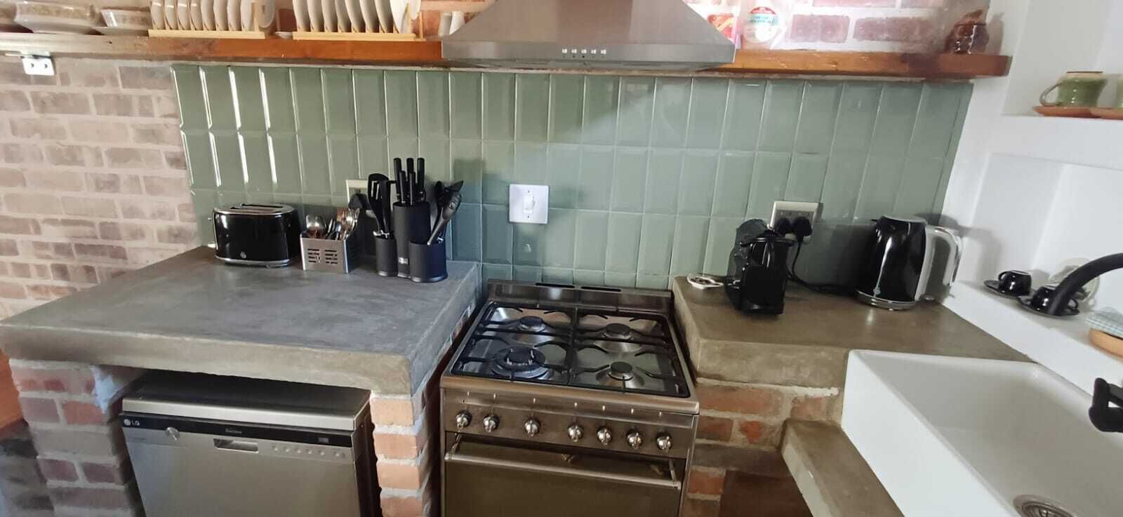 Een keuken met een gasfornuis, oven, vaatwasser en diverse keukengerei.