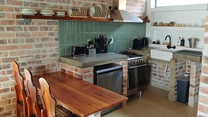Eine kleine Küche mit Backsteinwand, einem Holztisch und einfachen Geräten.