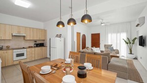 Una cocina moderna con armarios de madera, un refrigerador blanco y un comedor con una mesa de madera dispuesta para el desayuno.