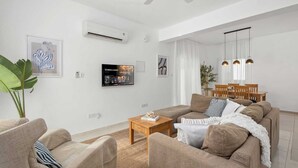 Una sala de estar moderna con un sofá, una mesa de centro y un televisor montado en la pared.