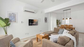 A modern living room with a sofa set, a coffee table, and a TV mounted on the wall.