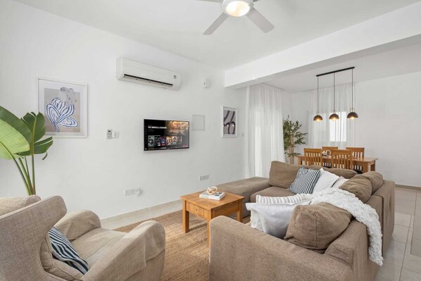 A modern living room with a sofa set, a coffee table, and a TV mounted on the wall.