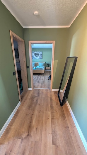 A hallway with a wooden floor leading to a bedroom with a bed and a wall-mounted artwork. - Luxurious vacation home in the heart of Winterberg (Winterberg)