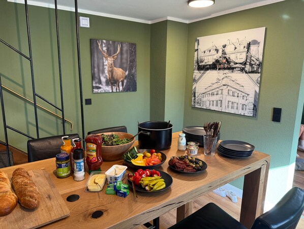 A dining table with various food items and condiments, a wooden cutting board with bread, and a painting of a deer on the wall. - Luxurious vacation home in the heart of Winterberg (Winterberg)