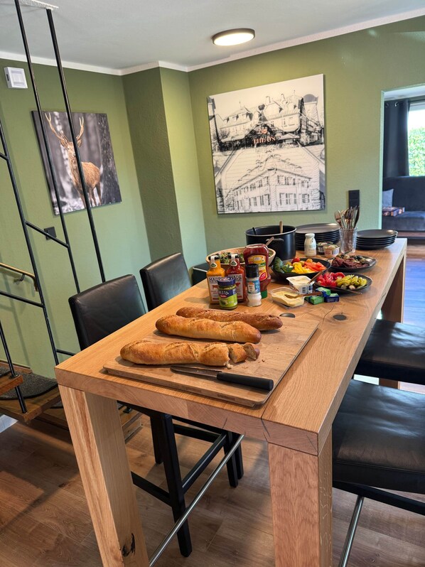 A dining area with a wooden table, chairs, and a variety of food items including bread, condiments, and vegetables. - Luxurious vacation home in the heart of Winterberg (Winterberg)