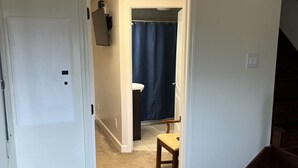 A hallway leading to a bathroom with a shower curtain, a toilet, and a chair. - Beautiful Room Just Waiting for You Pool IS Closed (Etowah)