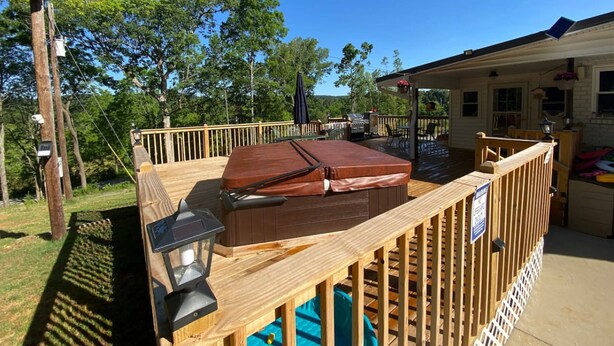 A wooden deck with a hot tub, outdoor furniture, and a covered area with a grill. - Beautiful Room Just Waiting for You Pool IS Closed (Etowah)
