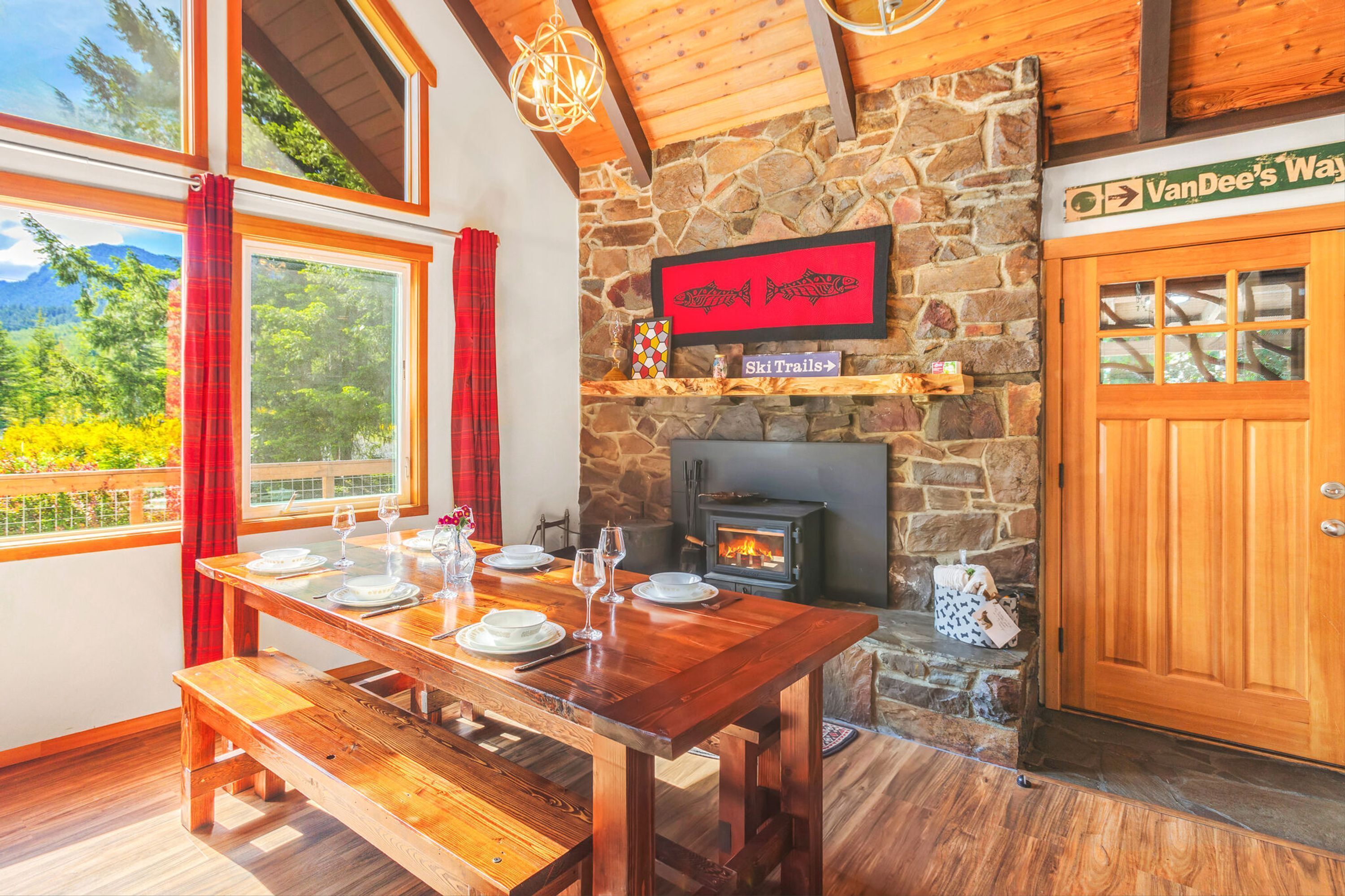 A wooden dining table set with plates and glasses, a stone fireplace, and a sign for VanDee's Way ski trails.