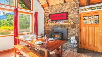 A wooden dining table set with plates and glasses, a stone fireplace, and a sign for VanDee's Way ski trails.