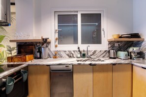 Een keuken met een inbouwvaatwasser, een raam met geëtste glas en een marmeren aanrecht.