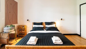 A neatly made bed with two pillows, a bedside table with a lamp, and a wall-mounted plant. - Stylish Jungle Retreat Kolonaki Center (Athens)