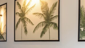 A living room with a grey sofa, patterned cushions, and framed artwork of palm trees on the wall. - Stylish Jungle Retreat Kolonaki Center (Athens)