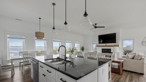 Una cocina amplia con una isla grande, muebles blancos y un comedor con mesa y sillas blancas.