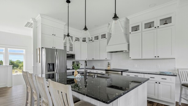Una cocina moderna con armarios blancos, una isla central e iluminación colgante.