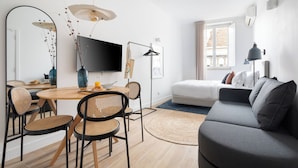 A modern living room with a grey sofa, a dining table with chairs, a flat-screen TV, and a large mirror. - Lapa Diplomatic Suite&Flat by FeelLisboa (Lisbon)