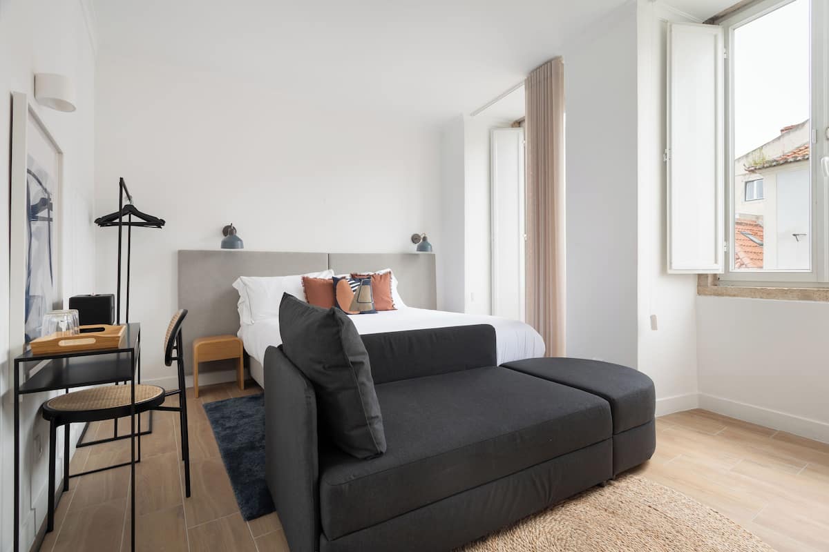 Un dormitorio moderno con cama, sofá, escritorio y silla.