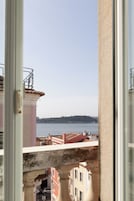 Vista desde una ventana con vista al agua y edificios al fondo.