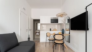 A modern, compact living space with a sofa, dining table, chairs, and a kitchen area. - Lapa Diplomatic Suite&Flat by FeelLisboa (Lisbon)