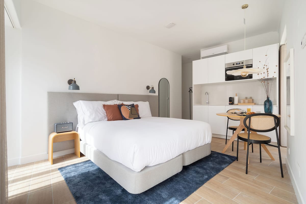 Un dormitorio moderno con una cama grande, una mesita de noche y un escritorio con sillas.