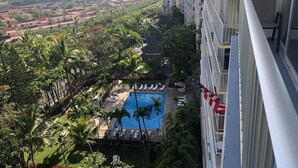 Un hôtel de grande hauteur doté d’une piscine entourée de palmiers et offrant une vue sur l’océan.