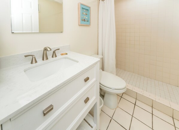 A bathroom with a white sink, two faucets, a toilet, and a shower curtain.