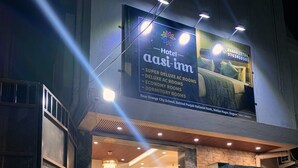 L’entrée d’un hôtel, avec une enseigne indiquant les différents types de chambres disponibles, notamment des chambres de luxe climatisées et des chambres économiques.