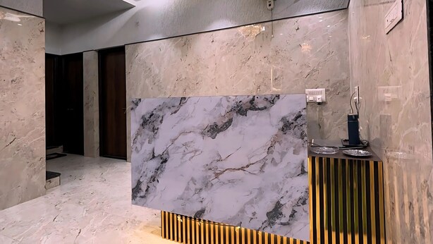 Un espace d’accueil moderne avec un mur en marbre, un lustre et un comptoir d’accueil à motifs rayés.