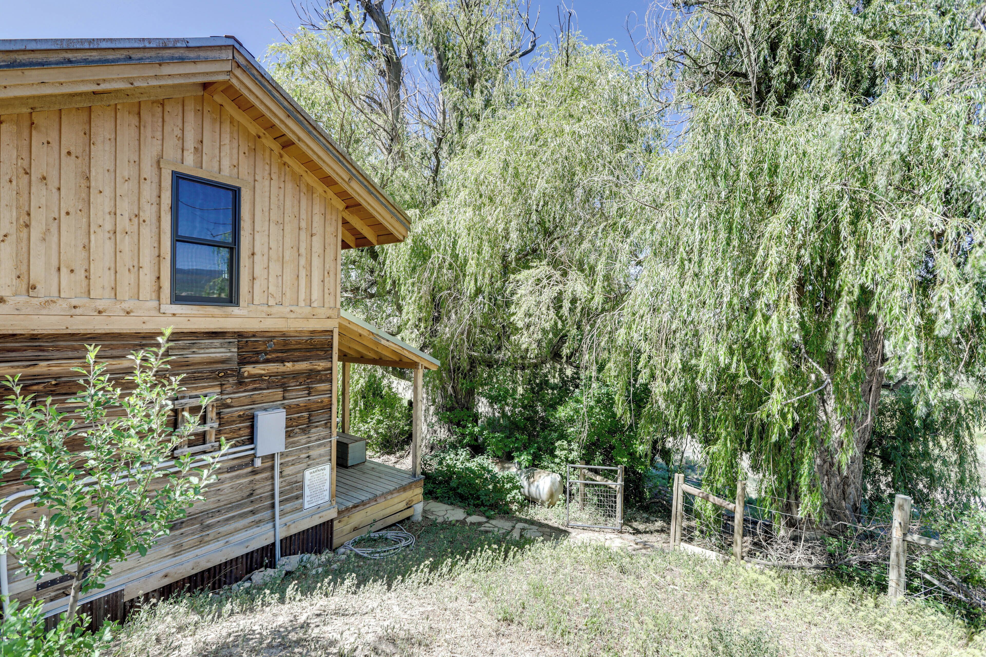 Eine Holzhütte mit Veranda, umgeben von Bäumen und einem eingezäunten Bereich.